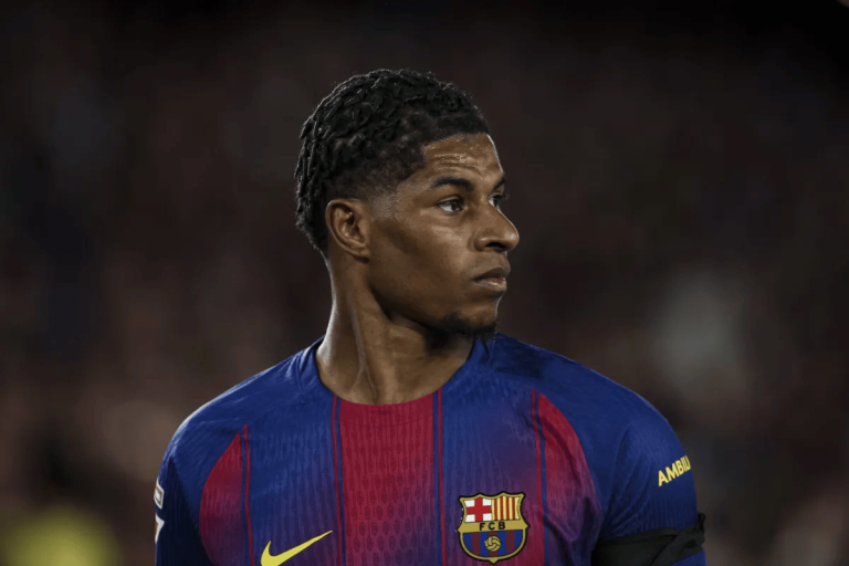 Soccer player in FC Barcelona kit looks to the right on the field with a focused expression.