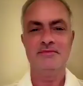 Close-up of a middle-aged man with a neutral expression in a white shirt against a beige wall.