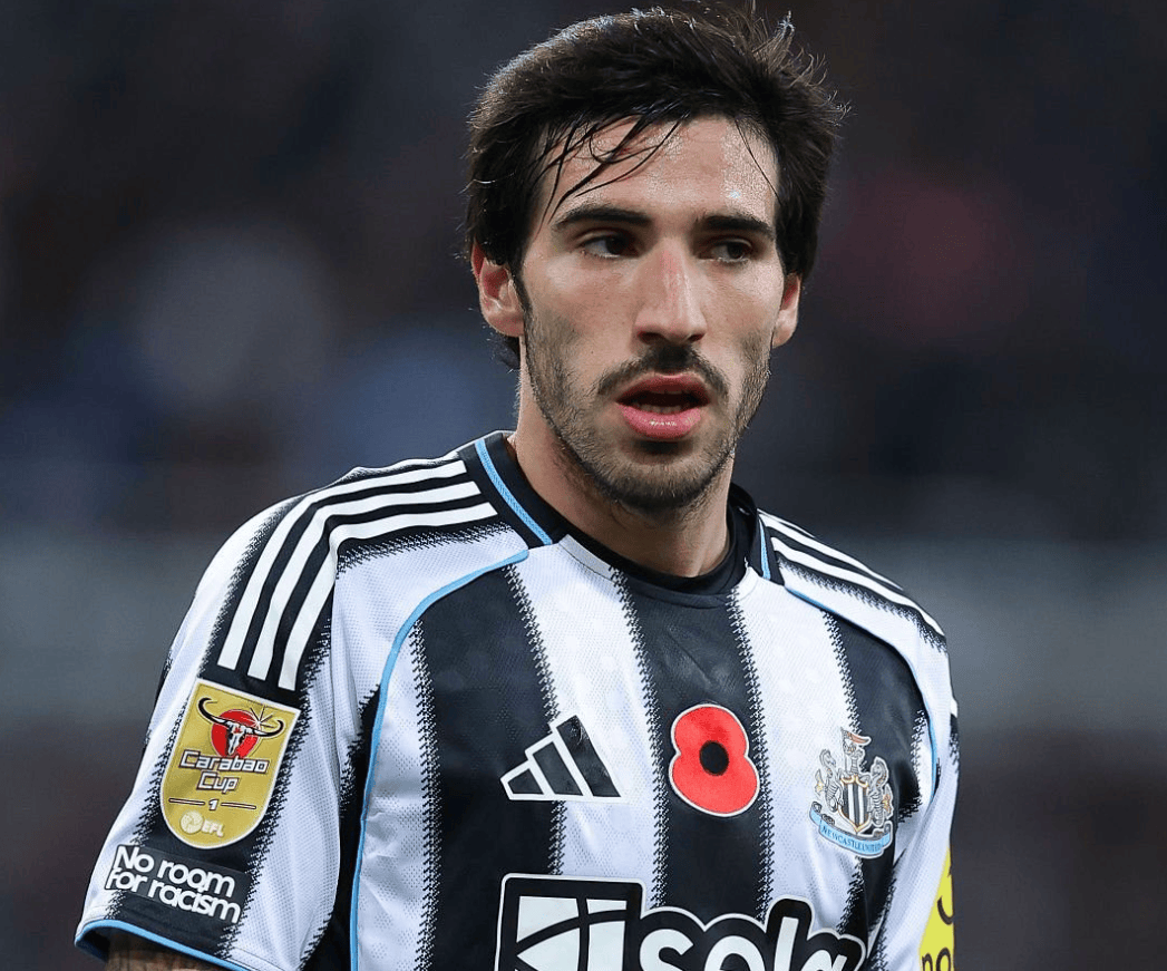 hupu-football-1780949365340-kaiyun-0png - 开云体育中心 Close-up of a male soccer player in a black-and-white striped jersey with a red poppy emblem, looking off to the side on a blurred field.