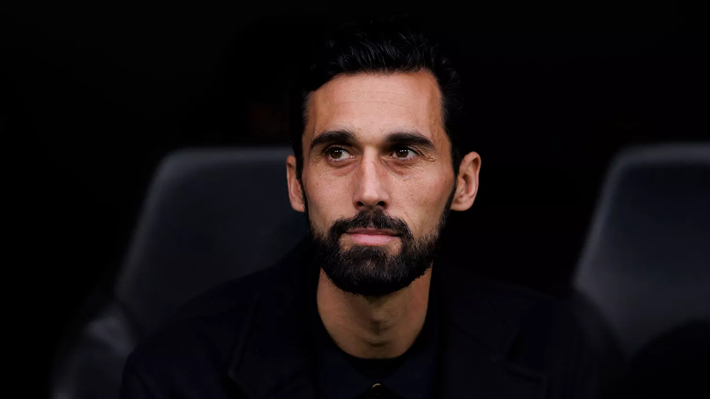 Close-up portrait of a man with dark hair and a full beard wearing black, gazing slightly to the right.
