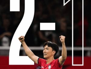 Soccer player in a red jersey celebrates with fists raised, overlaid by the scoreline 2–1.