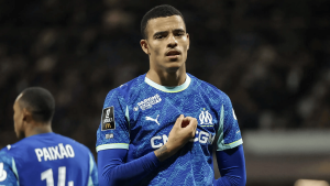 Soccer player in blue Marseille jersey adjusting his shirt during a match, stadium lights in the background