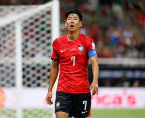 South Korea soccer captain wearing a red jersey with number 7, standing on the pitch near the goal.